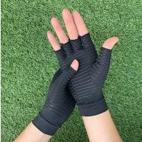 Hands wearing black fingerless Copper Compression Gloves Pain on green grass background